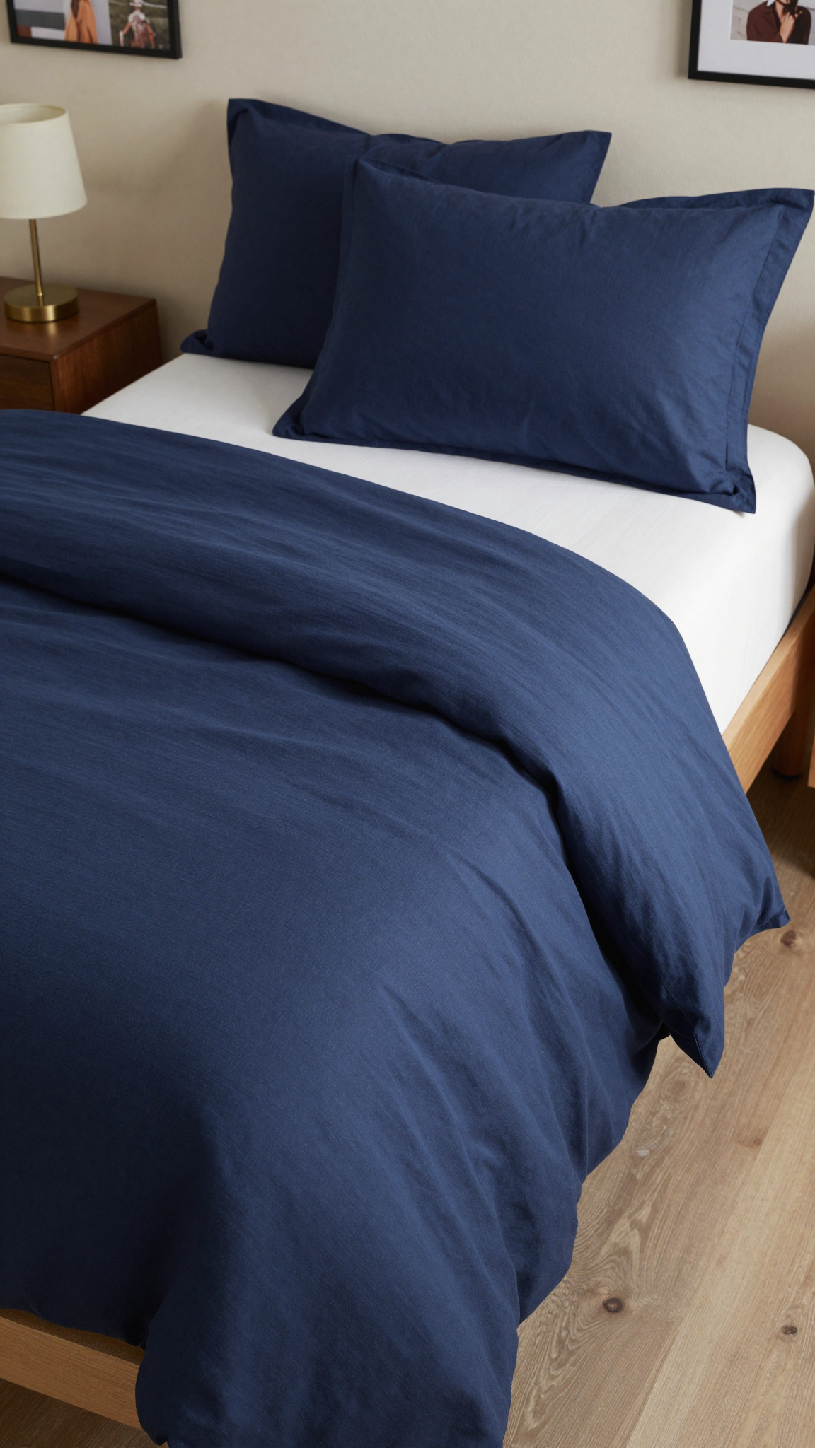 Amazon Basics 13-piece dorm bedding set in navy blue on a twin bed with a nightstand and lamp