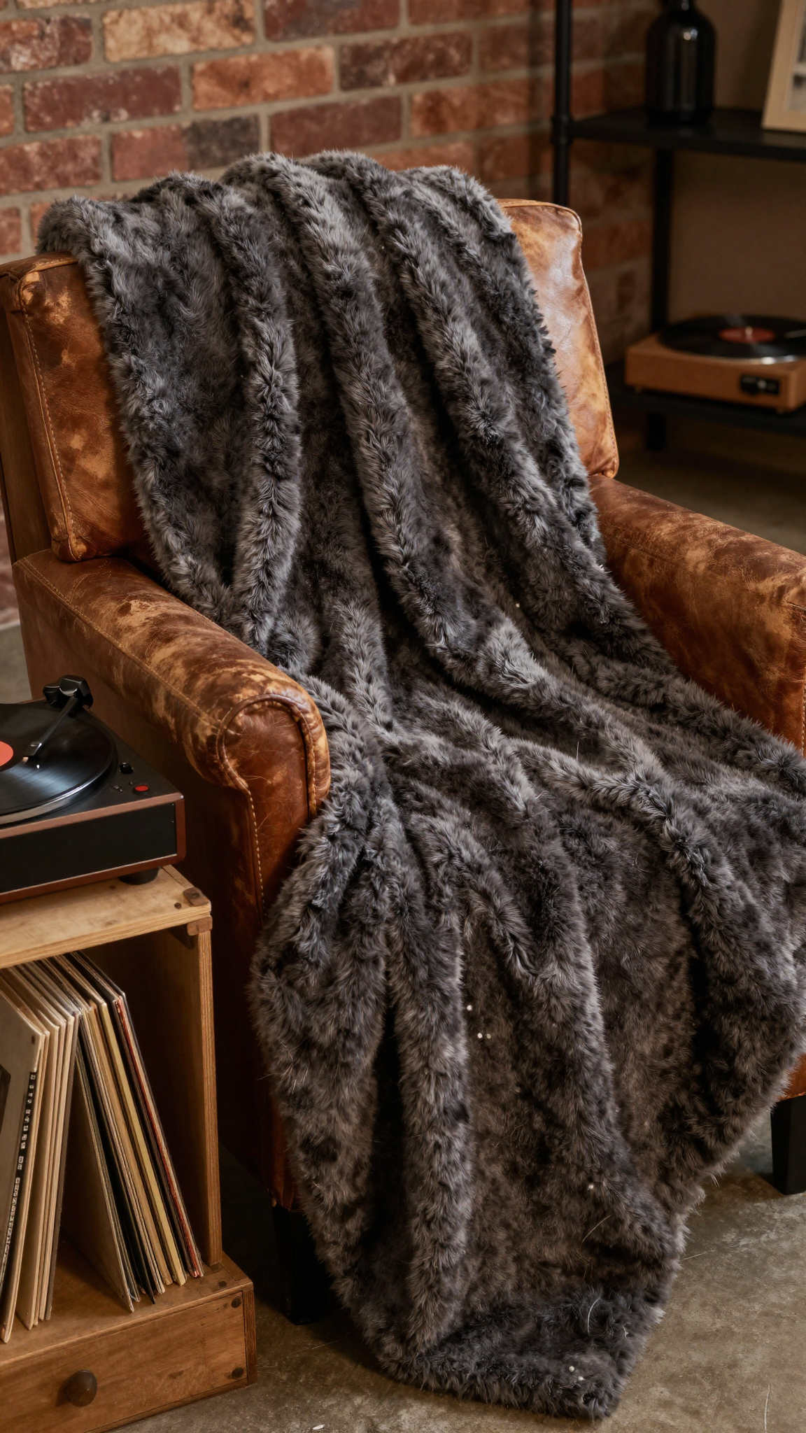 A chunky faux fur throw blanket draped over a leather armchair with a vintage record player nearby